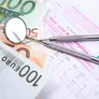 Zahn&auml;rztliche Instrumente auf verschiedenen Euro-Banknoten und einem Heil- und Kostenplan